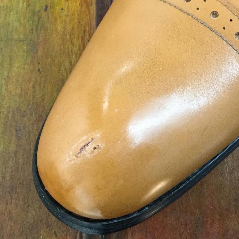 Dziura w skórze na eleganckich butach w eksponowanym miejscu - noski butów. Można zastosować płynną skórę.